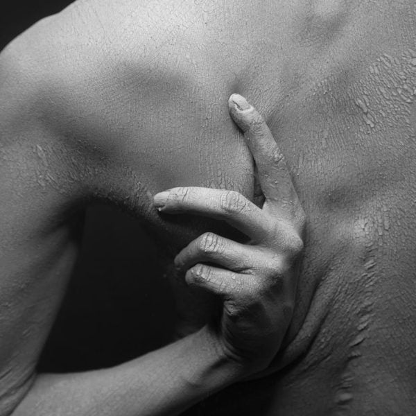 close up of a person scratching the dry and flaky skin of his back in black and white